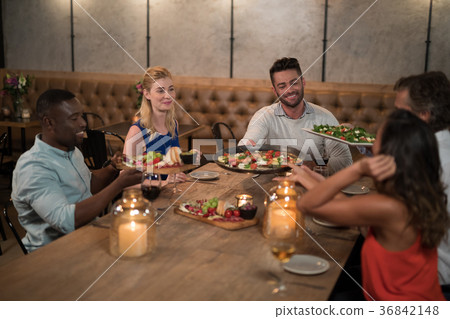 Friends passing food to each other while dining Friends passing food to each other while dining 36842148