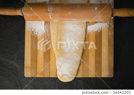 Directly above shot of wooden rolling pin on dough over cutting board Directly above shot of wooden rolling pin on dough over cutting board 36842203