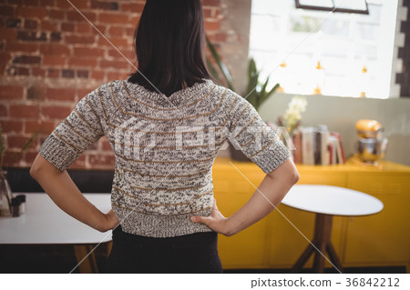 Rear view of young woman standing with hands on hip Rear view of young woman standing with hands on hip 36842212