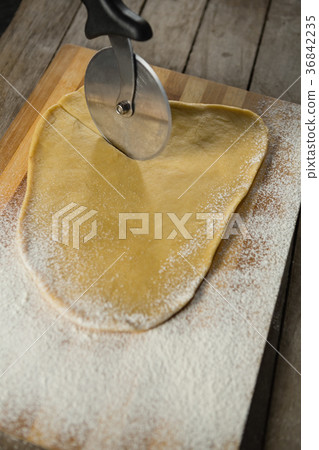 Cropped image of pastry cutter cutting dough Cropped image of pastry cutter cutting dough 36842235