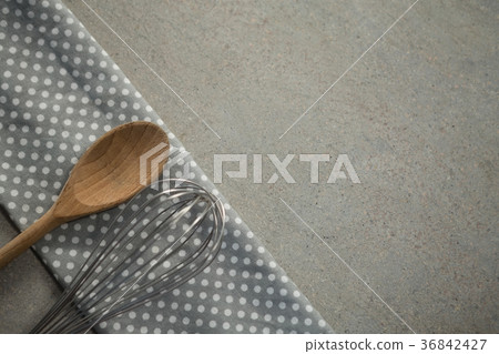 High anlge view of wooden spoon with wire whisk on folded napkin High anlge view of wooden spoon with wire whisk on folded napkin 36842427