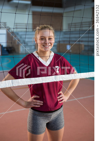 Smiling female volleyball player standing with hand on hips in the court 36842532