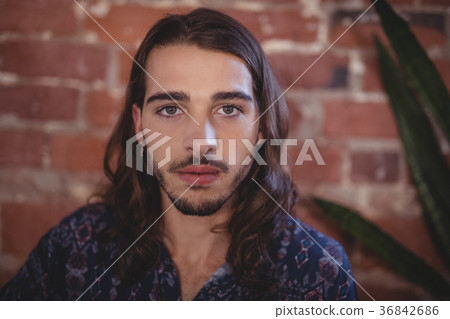 Close up portrait of confident young male photographer against brick wall Close up portrait of confident young male photographer against brick wall 36842686