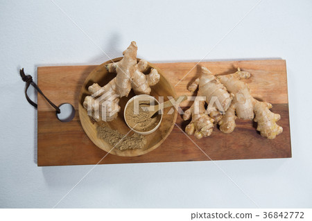 High angle view of fresh ginger and powder on wooden serving board High angle view of fresh ginger and powder on wooden serving board 36842772