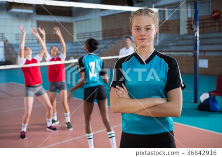 Smiling female volleyball player standing with arms crossed in the court 36842916