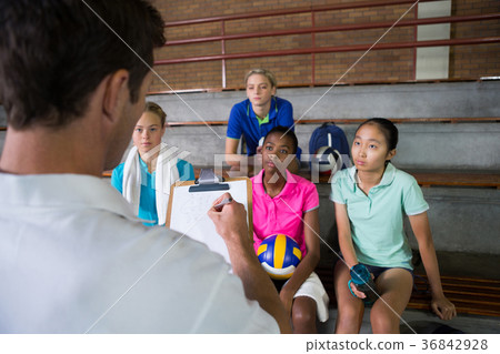 Volleyball coach discussing over clipboard with female player Volleyball coach discussing over clipboard with female player 36842928