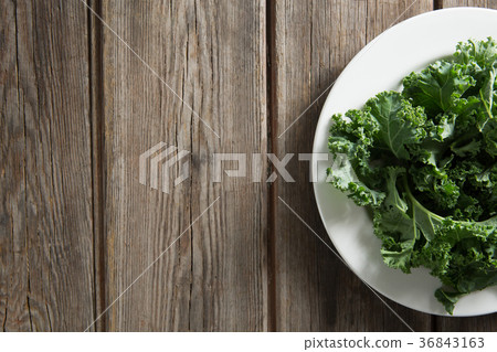 Kale vegetable in plate on wooden table 36843163