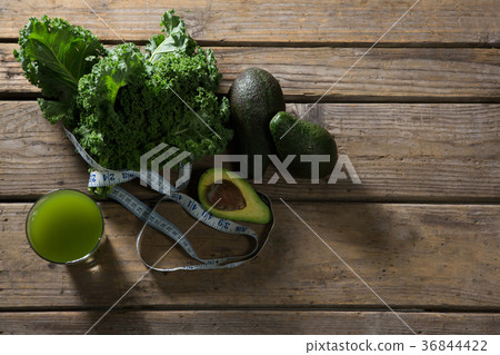 Mustard greens, avocado, measuring tape and juice on wooden table 36844422