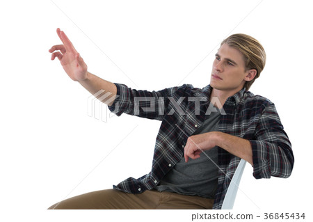 Businessman touching imaginary interface while sitting on chair Businessman touching imaginary interface while sitting on chair 36845434