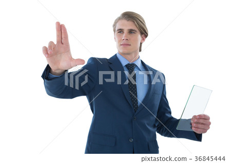 Confident businessman holding glass interface while touching imaginary screen Confident businessman holding glass interface while touching imaginary screen 36845444