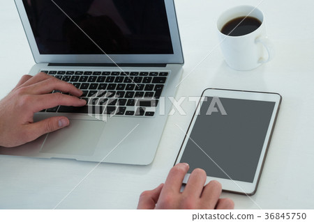 Cropped hands of businessman using laptop and tablet computer Cropped hands of businessman using laptop and tablet computer 36845750