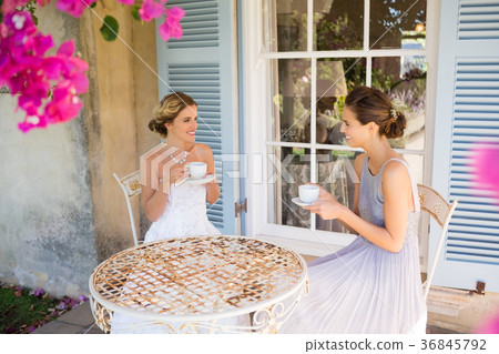 Bride and bridesmaid having coffee in yard 36845792