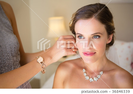 Bridesmaid dressing bride in fitting room 36846339