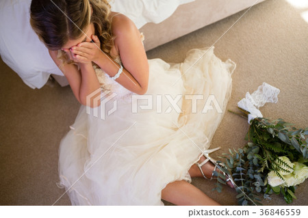 High angle view of bride in wedding dress crying while sitting by bed 36846559