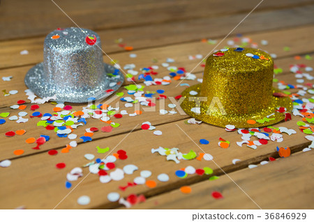 Golden and silver hat with confetti on wooden surface 36846929