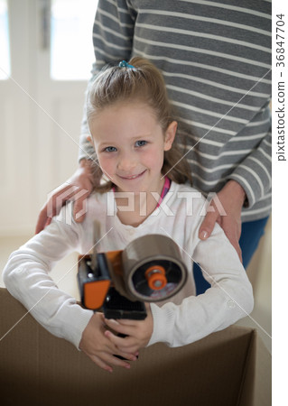 Father and daughter opening cardboard boxes in living room 36847704