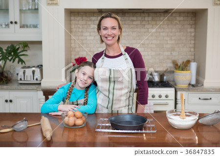 Smiling mother and daughter standing in the kitchen Smiling mother and daughter standing in the kitchen 36847835