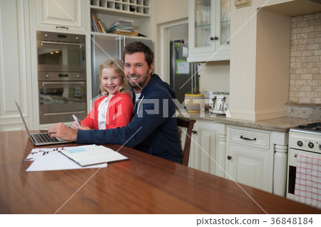 Father and daughter working on laptop at home 36848184