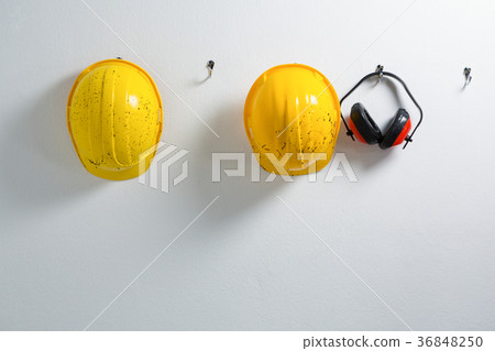 Hard hats and earmuffs hanging on hook Hard hats and earmuffs hanging on hook 36848250