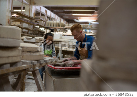 Male potter assisting girl in molding a clay Male potter assisting girl in molding a clay 36848552