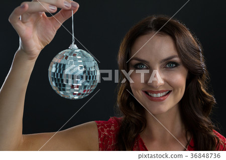 Smiling woman holding mirror ball against black background Smiling woman holding mirror ball against black background 36848736