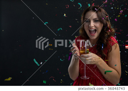 Woman celebrating the New year with falling confetti streamers and champagne 36848743