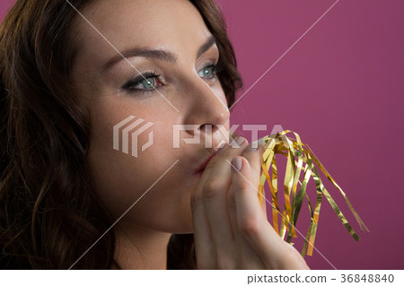 Woman in sliver hat blowing party horn Woman in sliver hat blowing party horn 36848840