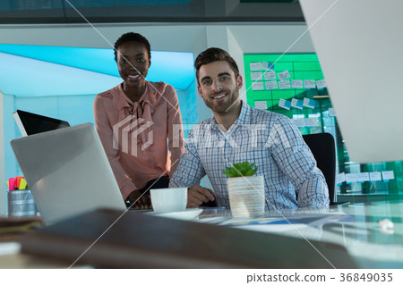 Portrait of smiling executives working together at desk Portrait of smiling executives working together at desk 36849035