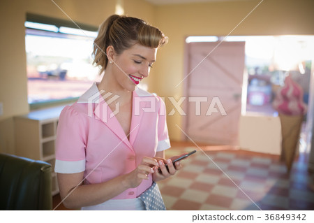 Waitress using mobile phone in restaurant Waitress using mobile phone in restaurant 36849342