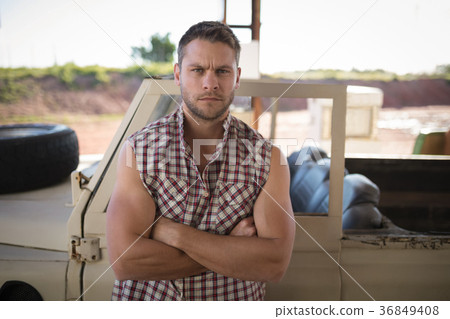 Man standing with arms crossed near his car Man standing with arms crossed near his car 36849408