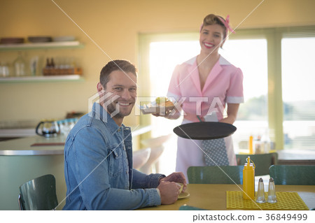 Waitress serving meal to man in restaurant 36849499