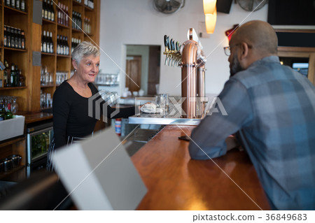 Man talking to senior waitress at counter 36849683