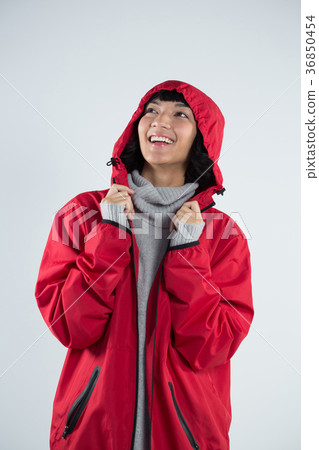 Woman in hooded jacket standing against white background 36850454