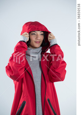 Woman in hooded jacket standing against white background Woman in hooded jacket standing against white background 36850538