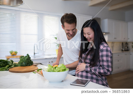 Pregnant couple preparing salad together in the kitchen 36851863