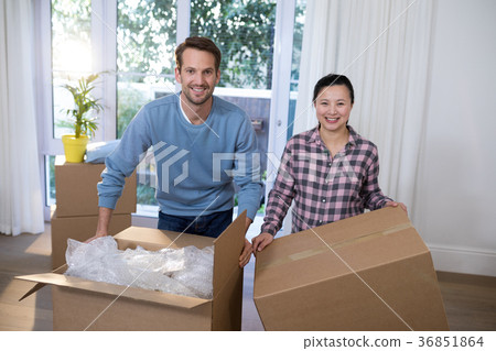 Smiling couple with cardboard boxes sitting at their new home 36851864