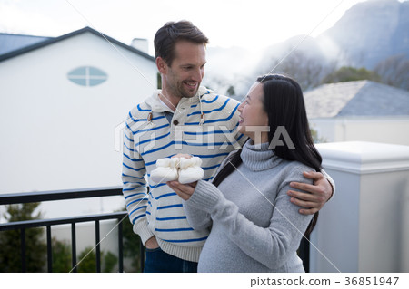 Pregnant woman and her husband holding baby socks in balcony 36851947