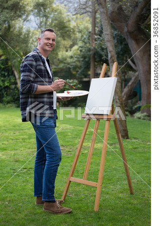 Man painting on canvas in garden 36852091