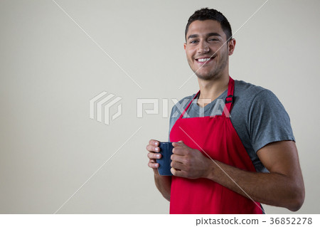 Smiling waiter holding a cup of coffee Smiling waiter holding a cup of coffee 36852278