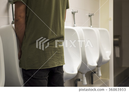 young man using a urinal in a public washroom 36863933