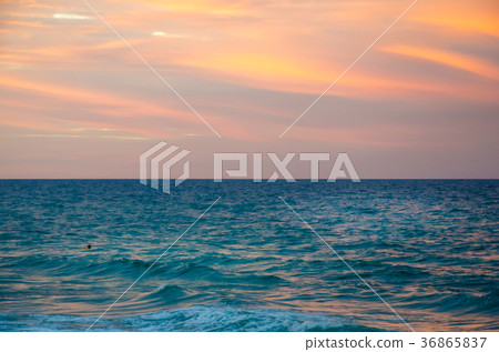 Sunset at the beach with tourists enjoying 36865837