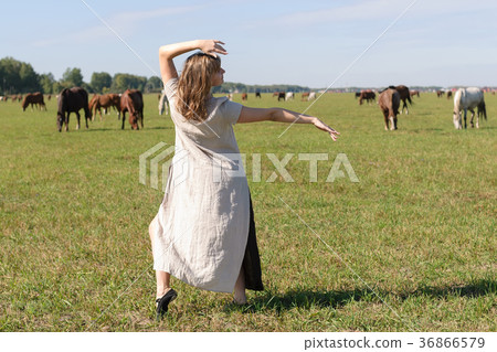 Attractive girl dances on meadow with horses 36866579