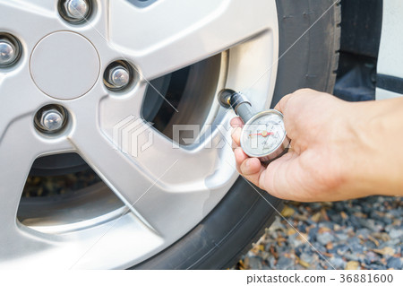 mechanic hands checking tire pressure using gauge 36881600
