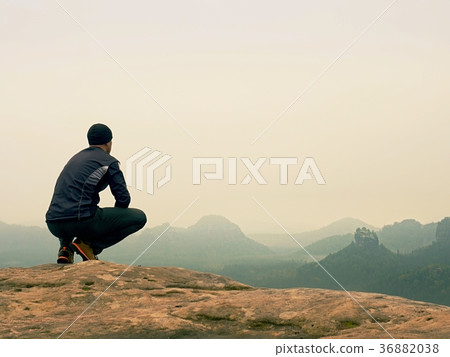 Nature hiker on sharp cliff roc watching over mist 36882038