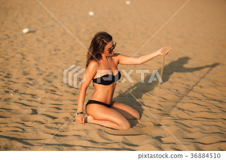 Sexy girl sunbathing on a beach and plays with 36884510