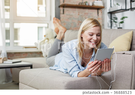 Happy girl enjoying interesting film on tablet Happy girl enjoying interesting film on tablet 36888523