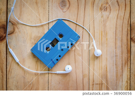 Cassette tape and white earphone on wooden table 36900056