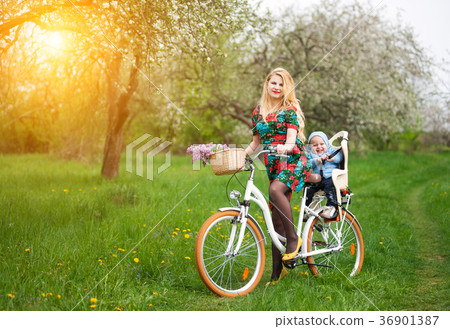Blonde female riding city bicycle with baby in bicycle chair Blonde female riding city bicycle with baby in bicycle chair 36901387