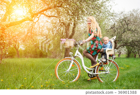Blonde female riding city bicycle with baby in bicycle chair Blonde female riding city bicycle with baby in bicycle chair 36901388