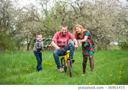 Father teaching son to ride a bike by his example 36901455